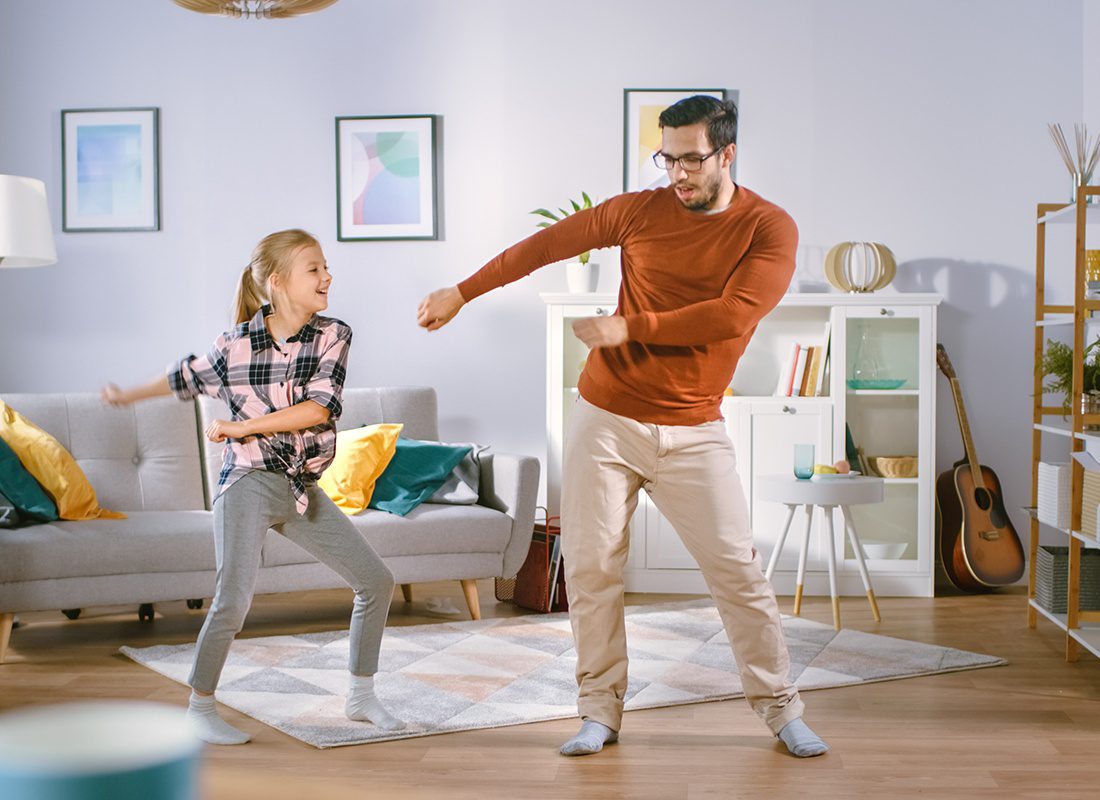 About Our Agency - Happy Little Girl Dances With Young Father in the Middle of the Living Room